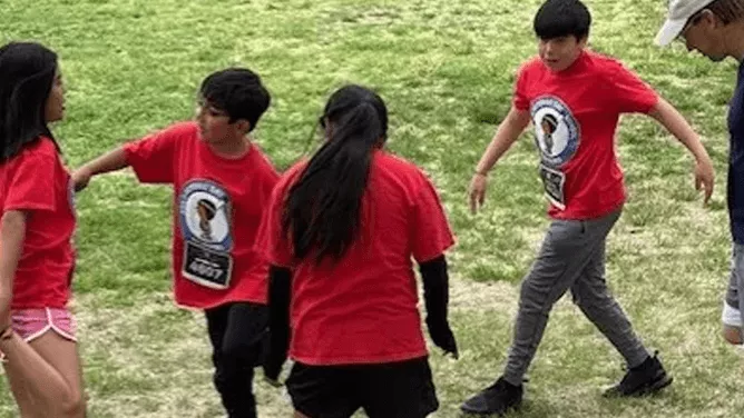 Four students in red shirts stretching before a running club.