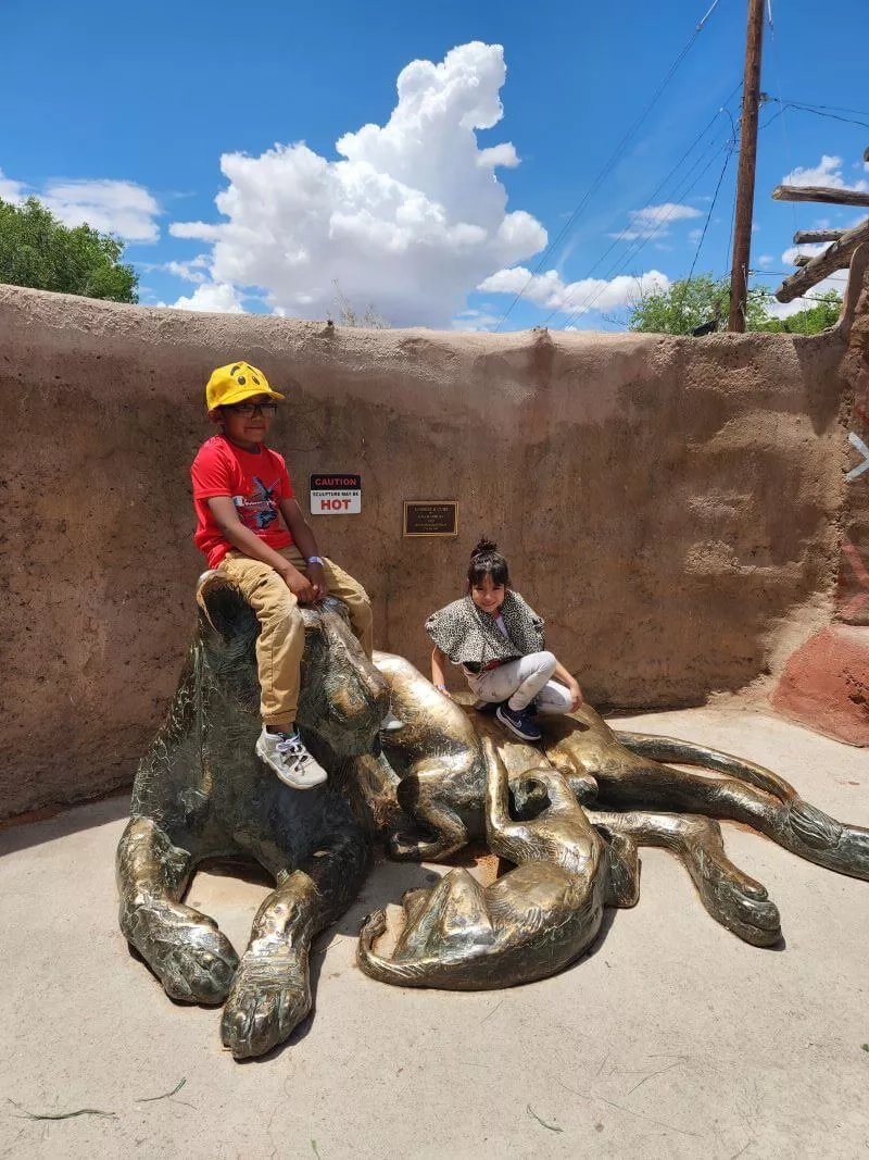 Students on field trip sitting on statue at the zoo.