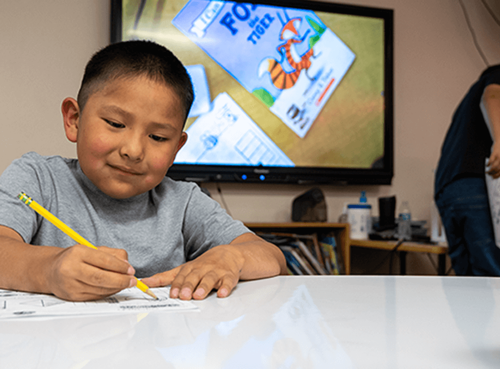 Young male student writing on a desk in class.