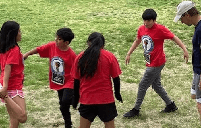 Four students in red shirts stretching before a running club.  