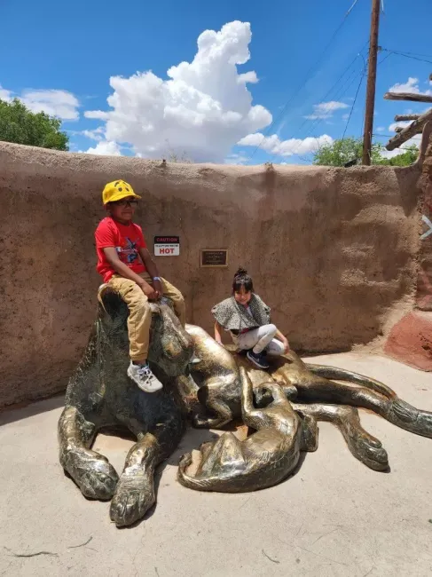 Students on field trip sitting on statue at the zoo.
